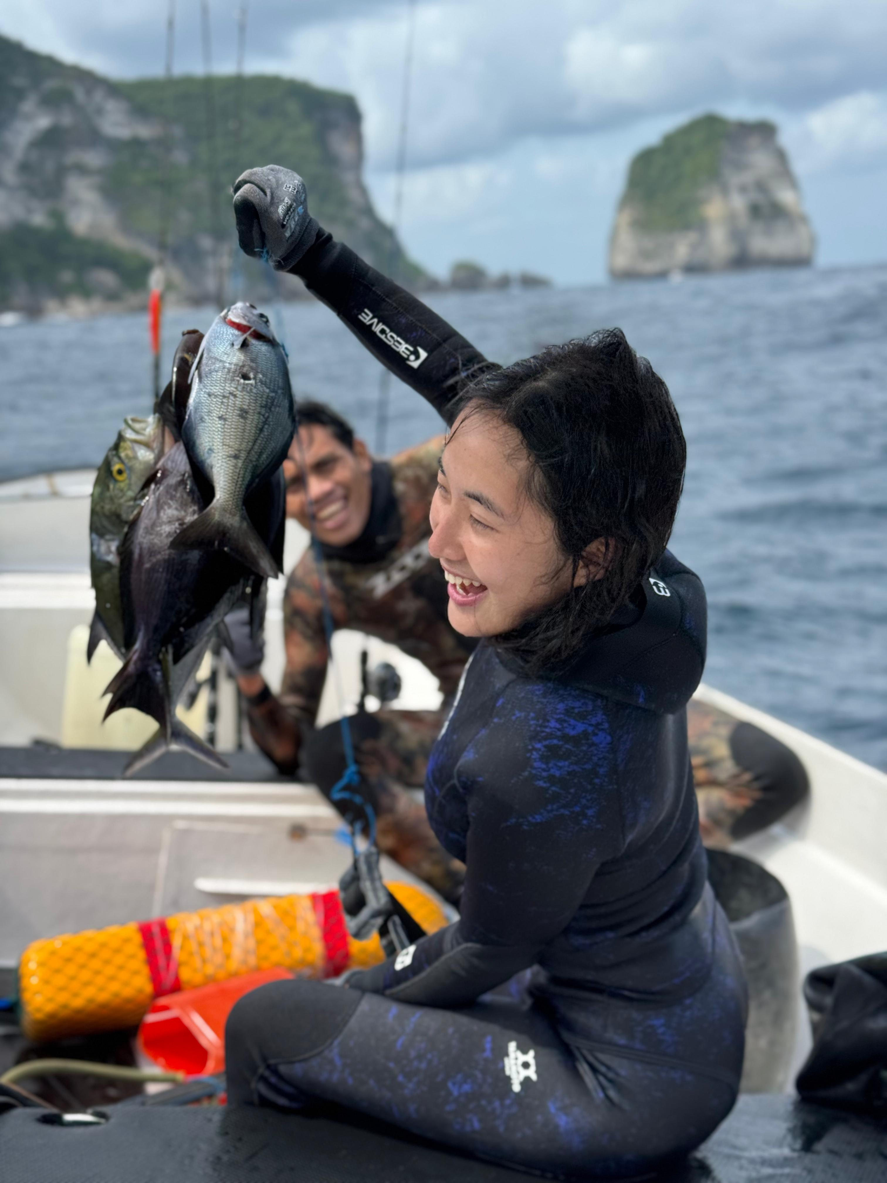 Happy guest and Jaya with a big catch, dramatic sea stacks behind