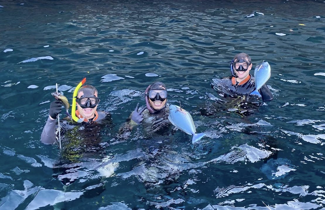 Group in the water holding fish, all smiling